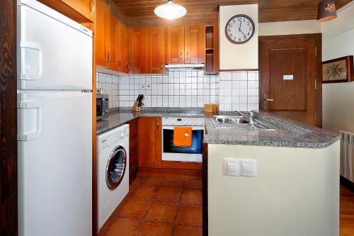 Apartamento La Santeta de Aran في فييا: مطبخ مع ثلاجة بيضاء وغسالة صحون
