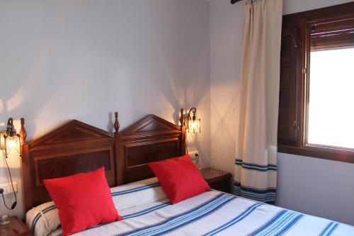 Un dormitorio con una cama con almohadas rojas y una ventana en Apartamentos Rurales Rosendo: "Suite Veleta" en Capileira