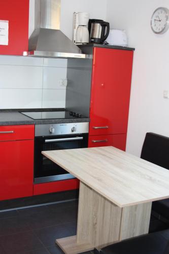 a kitchen with red cabinets and a wooden table at Ahoi-Gästehaus in Hamburg