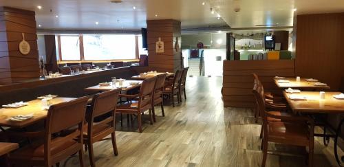 a restaurant dining room with wooden tables and chairs at Regenta Place Bangalore, Cunningham Road in Bengaluru