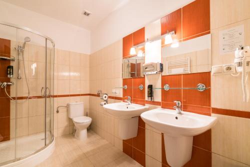 a bathroom with two sinks and a toilet and a shower at Kúria Beckov - Penzión in Beckov