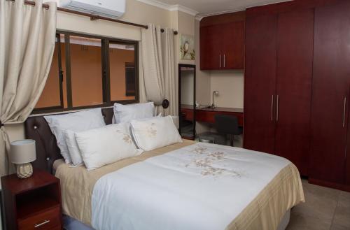 a bedroom with a large white bed with wooden cabinets at DYNA GUEST HOUSE in Durban