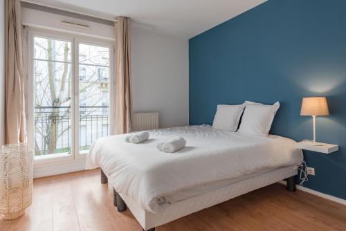 une chambre avec un grand lit avec un mur bleu dans l'établissement Standing apartment in Disneyland BMYGUEST, à Serris