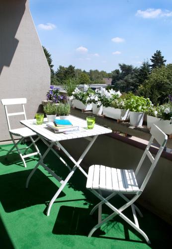 a table and chairs on a balcony with potted plants at Rheinhof by Gerda Good Living - Digital Access in Meerbusch