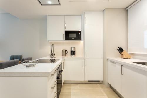 a kitchen with white cabinets and a microwave at Pine Cliffs Gardens in Albufeira