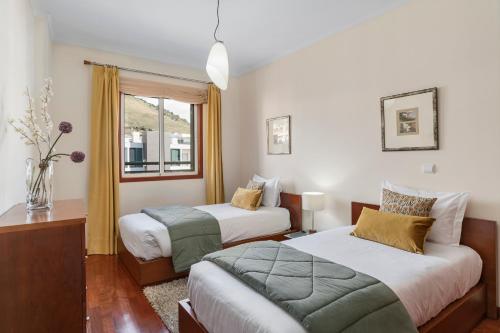 a bedroom with two beds and a window at Ajuda III by An Island Apart in Funchal