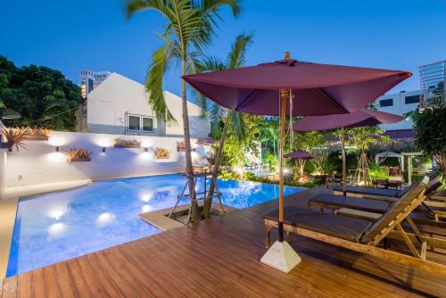 uma piscina com um guarda-sol e espreguiçadeiras e uma piscina em Anchan Hotel & Spa em Hua Hin