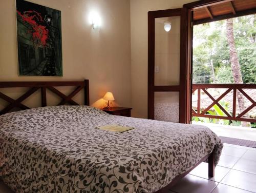 a bedroom with a bed and a large window at Castelinho de Paraty in Paraty