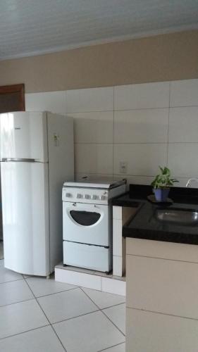 a kitchen with a white stove and a refrigerator at Apartamento inteiro 2 quartos Wi-Fi in Montes Claros