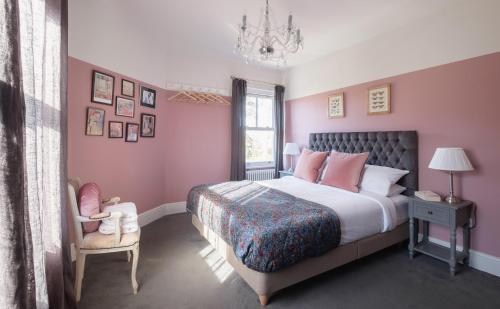 a bedroom with pink walls and a bed and a chair at The Victorian Post House - Central Frome in Frome