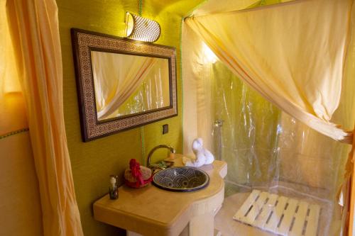 a bathroom with a table with a mirror and a sink at Sahara Desert Luxury Camp in Merzouga