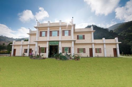 a large house on a grass field with mountains in the background at ChunYang Homestay春陽一品居 in Renai