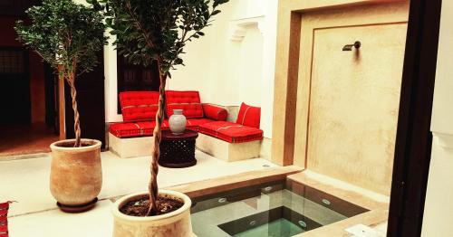 uma sala de estar com dois vasos de árvores e um sofá vermelho em Riad Les 5 Soeurs em Marrakech