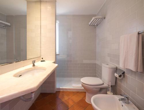 a bathroom with a toilet and a sink and a tub at Dom Pedro Lagos in Lagos