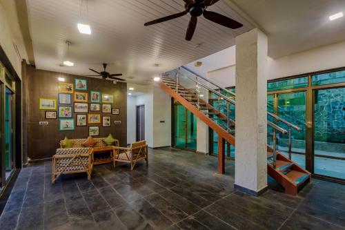 a living room with a ceiling fan and a staircase at SaffronStays Bellini, Karjat in Kalamb