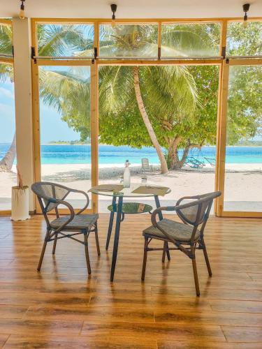 a table and chairs with a view of the beach at Thundi Village & Spa in Maalhos