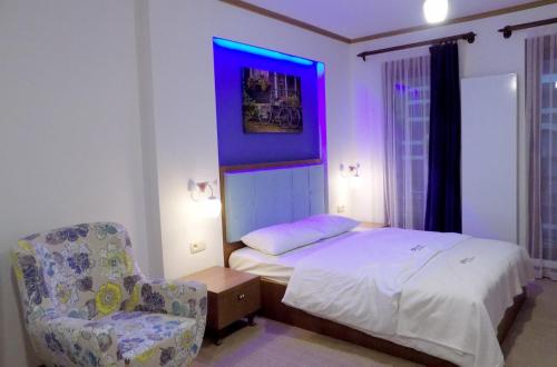 ein Schlafzimmer mit einem Bett und einem Stuhl mit einem lila Licht in der Unterkunft Fly inn Hotel Lounge in Machelen