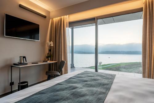 a bedroom with a large window with a view of the water at Golden Lakes Hotel in Boussu-lez-Walcourt