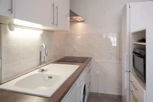 une cuisine blanche avec un évier et une cuisinière dans l'établissement Maison Borrel, à Carcassonne