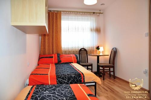 1 dormitorio con 2 camas y 1 mesa con ventana en "Nad Zdrojami" Domek Kowalczyk 691-739-603, en Szczawnica