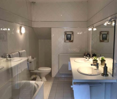 a bathroom with two sinks and a toilet at Manoir de Rieuzal in Loubressac
