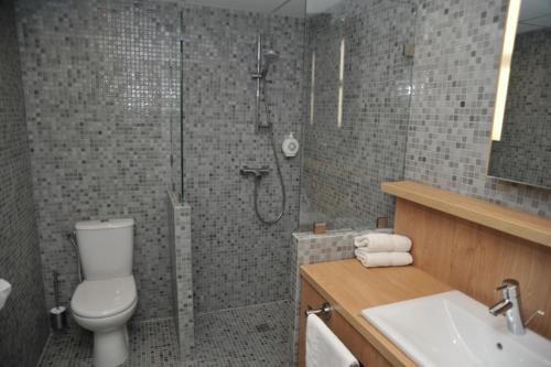 a bathroom with a shower and a toilet and a sink at Hotel Espace Cite in Carcassonne