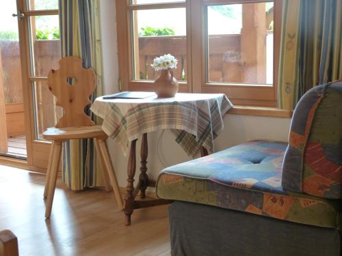 einen Tisch mit einem Stuhl und eine Vase Blumen darauf in der Unterkunft Suzanne's B&B & Gardens in Füssen