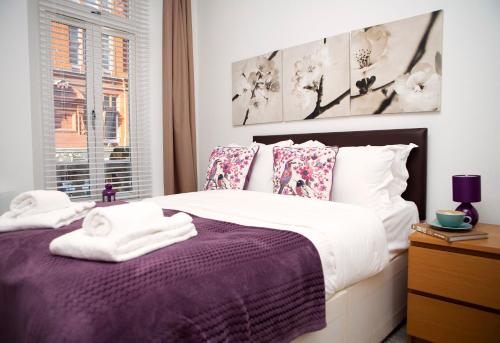 a bedroom with a purple bed with towels on it at Apt 1, Trafalgar Square 1st Floor by Indigo Flats in London
