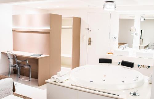 a bathroom with a large white tub and a sink at Hotel Rieger in Balneário Camboriú