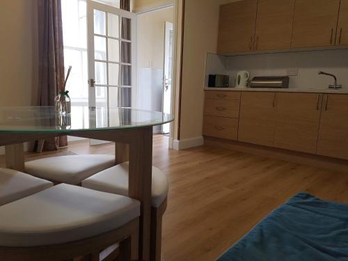 cocina con mesa de cristal y algunas sillas en Thorshaven Apartment, Orkney, en St Margaret's Hope