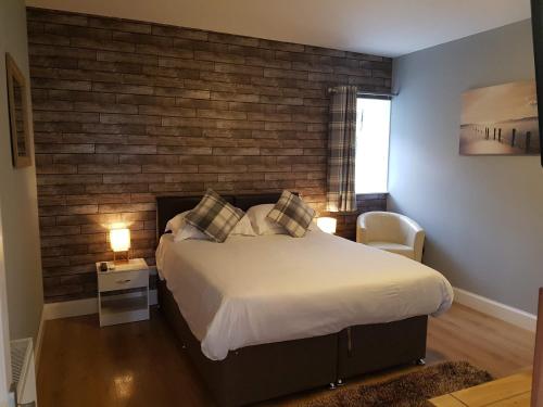 um quarto com uma cama grande e uma parede de tijolos em Thorshaven Apartment, Orkney em St Margaret's Hope