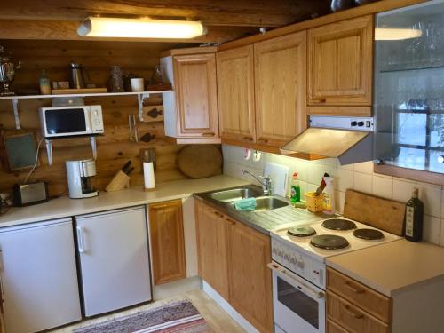 a kitchen with white appliances and wooden cabinets at Villa Luppopirtti in Luosto