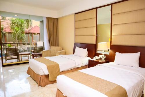a hotel room with two beds and a balcony at Bela International Hotel & ConventionTernate in Ternate