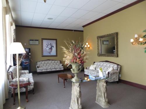 a waiting room with couches and a table with flowers on it at Motel Cofotel in Saint-Siméon