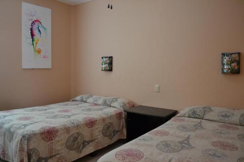 a bedroom with two beds and a picture on the wall at Hotel Maya in Guadalajara