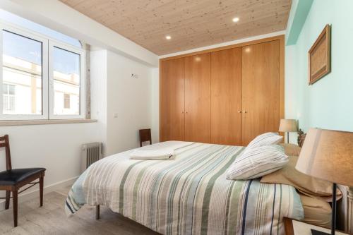 Un dormitorio con una cama con cabecero de madera. en As Serenas Casa C, en Vila Nova de Cacela