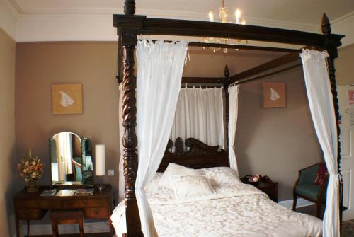 a bedroom with a canopy bed and a mirror at The Bank House Hotel in Uttoxeter