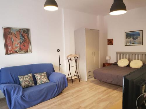 ein Wohnzimmer mit einem blauen Sofa und einem Bett in der Unterkunft Estudio 54 Centro in Alicante