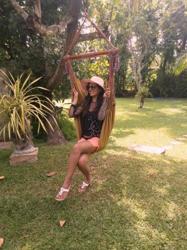 a woman sitting in a hammock in a park at Good Karma Villa in Bentota