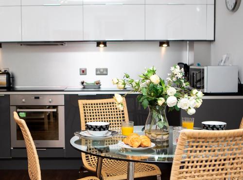 a kitchen with a table with a vase of flowers at Apt 2, Trafalgar Square 2nd Floor by Indigo Flats in London