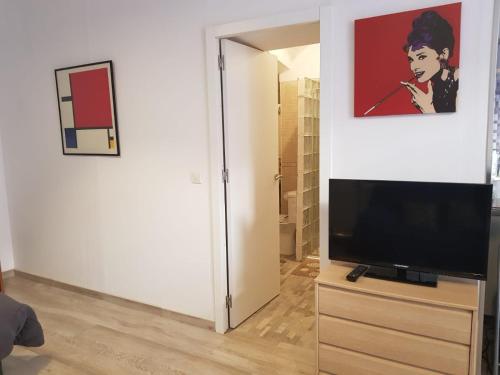 ein Wohnzimmer mit einem TV und einem Wandgemälde in der Unterkunft Estudio 54 Centro in Alicante