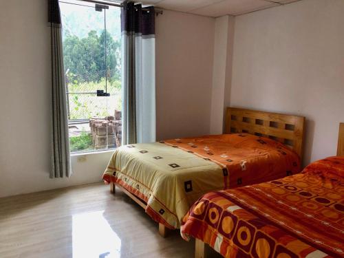 two beds in a room with a window at Hotel Bellavista in Huaran
