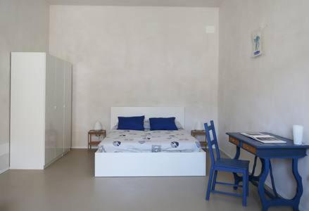 una camera con letto e tavolo con sedia blu di La Praya a Favignana
