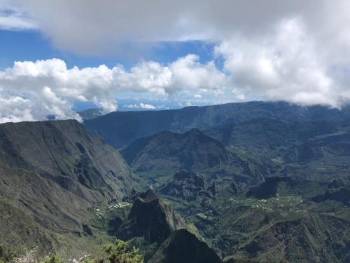 a view of a mountain range with clouds in the sky at Ferme l'Eau de Coco in Saint-Paul