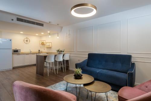 Una sala de estar con un sofá azul y una cocina. en Herzliya Marina Lagoon Apartment, en Herzliya