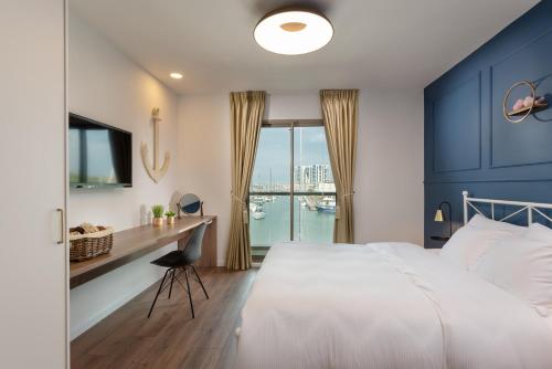 a bedroom with a bed and a desk with a window at Herzliya Marina Lagoon Apartment in Herzliyya B