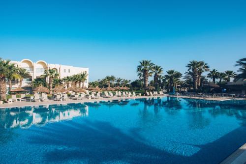 a large swimming pool with chairs and palm trees at Iberostar Waves Mehari Djerba in Taguermess