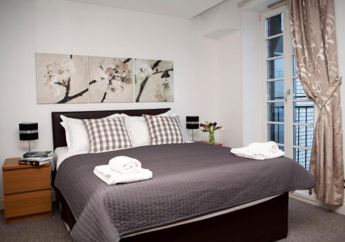 a bedroom with a bed with two towels on it at Apt 3, Trafalgar Sq Duplex, 3rd & 4th floor by Indigo Flats in London