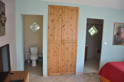 une salle de bain avec une porte en bois et des toilettes dans l'établissement Chambre d'Hôtes de l'Estuaire, à La Rivière-Saint-Sauveur