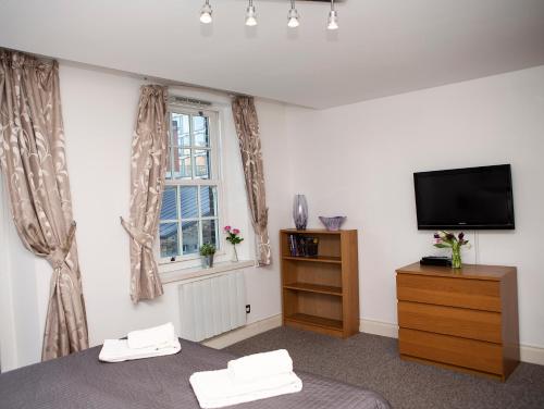 a bedroom with a bed and a tv and a window at Apt 3, Trafalgar Sq Duplex, 3rd & 4th floor by Indigo Flats in London